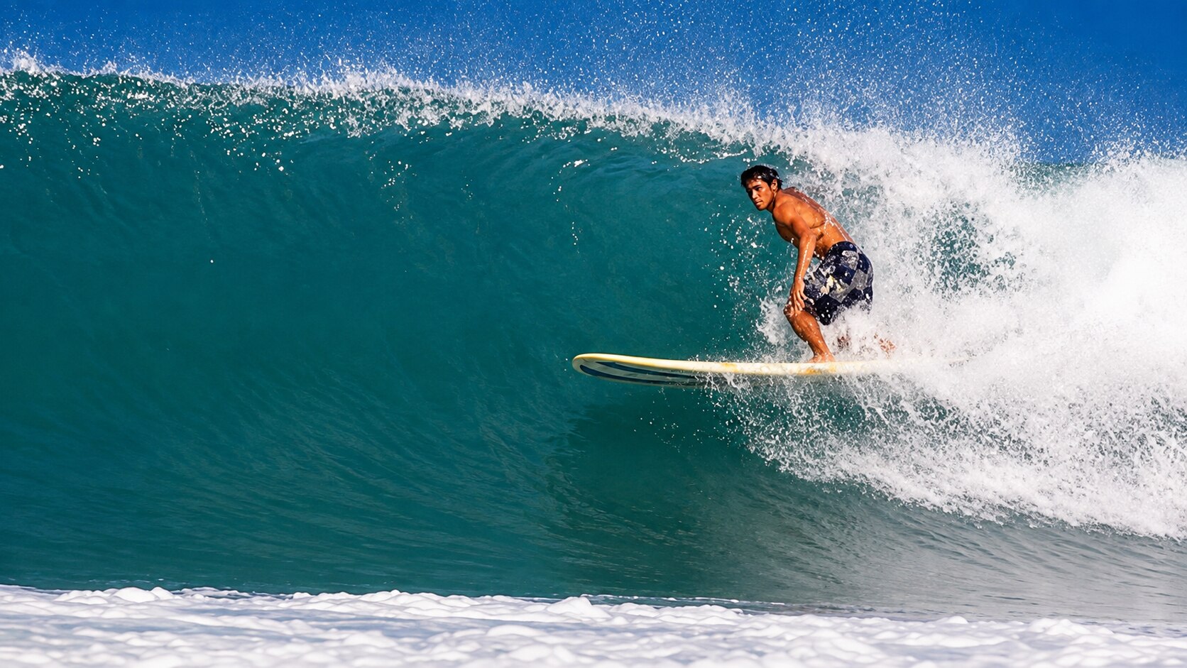 Surfer carving down a clean blue wave in San Felipe