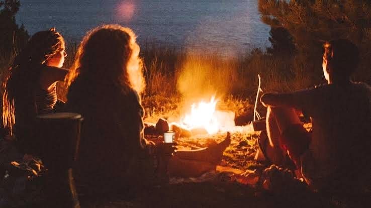 Guests gathered around a bonfire by the shore