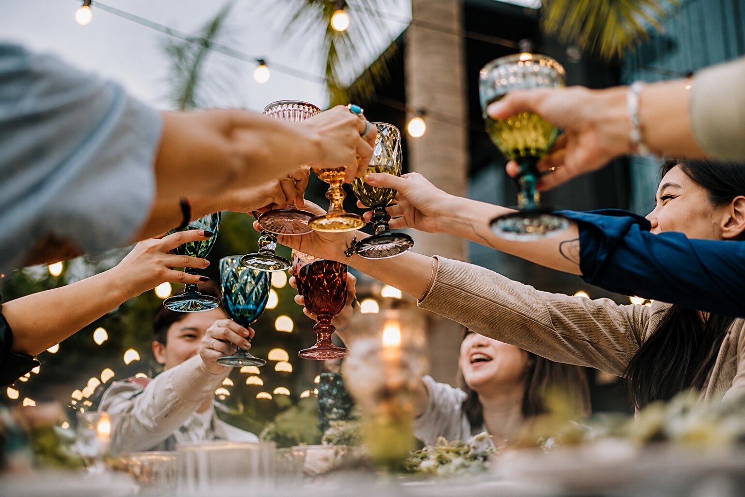 Friends raising glasses in a toast under string lights