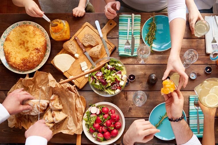 A shared table of plates, bread and salads at a long lunch
