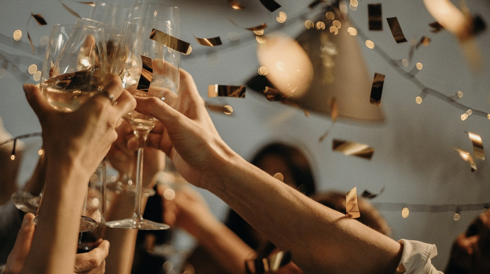 Friends raising glasses in a toast under string lights