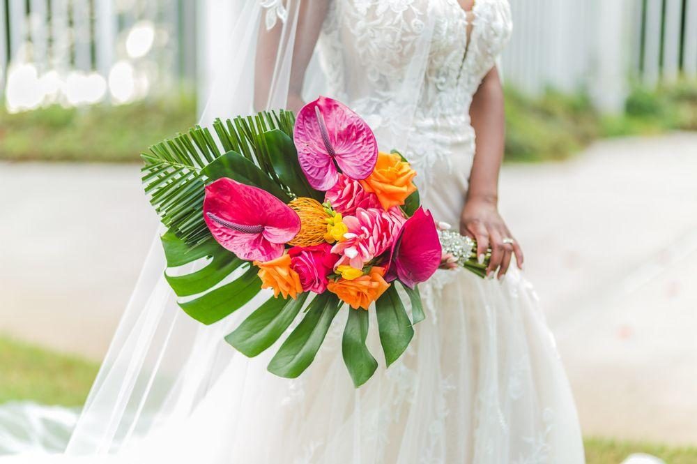 Bride holding a tropical bouquet of anthuriums, roses and monstera leaves