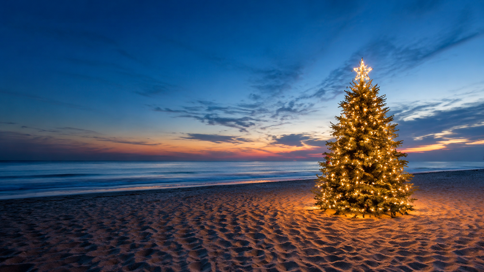 A Christmas tree glowing beside the sea at sunset in Zambales