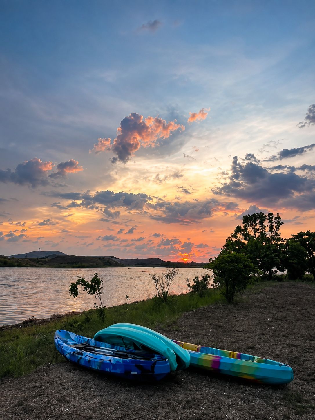 Kayaks resting by calm water at sunset
