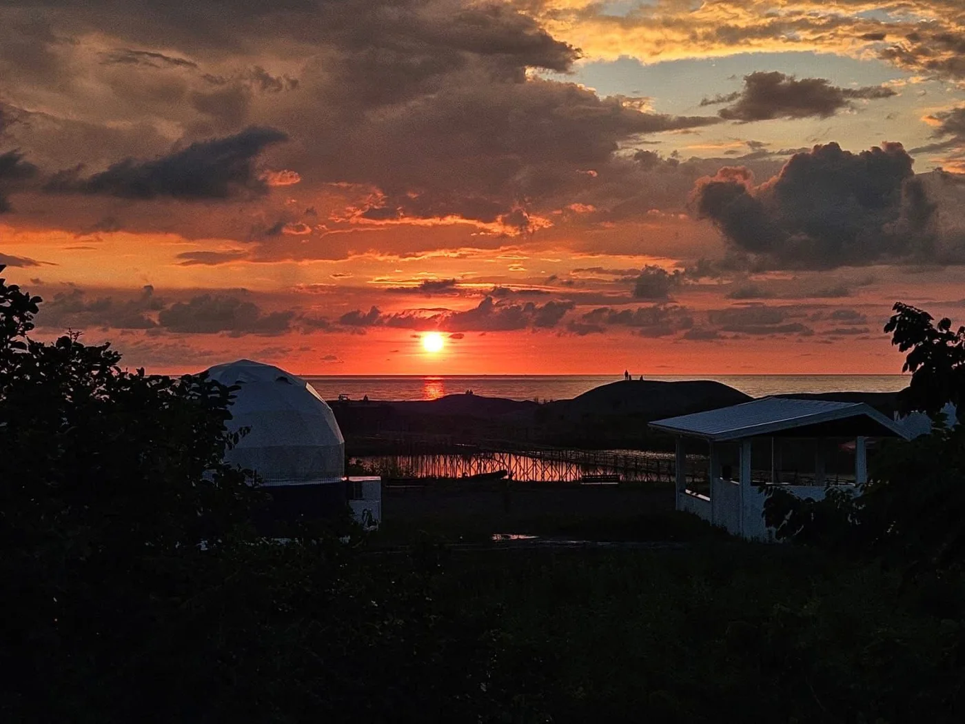 The sun setting into the sea beyond the dome, the bridge and the lagoon