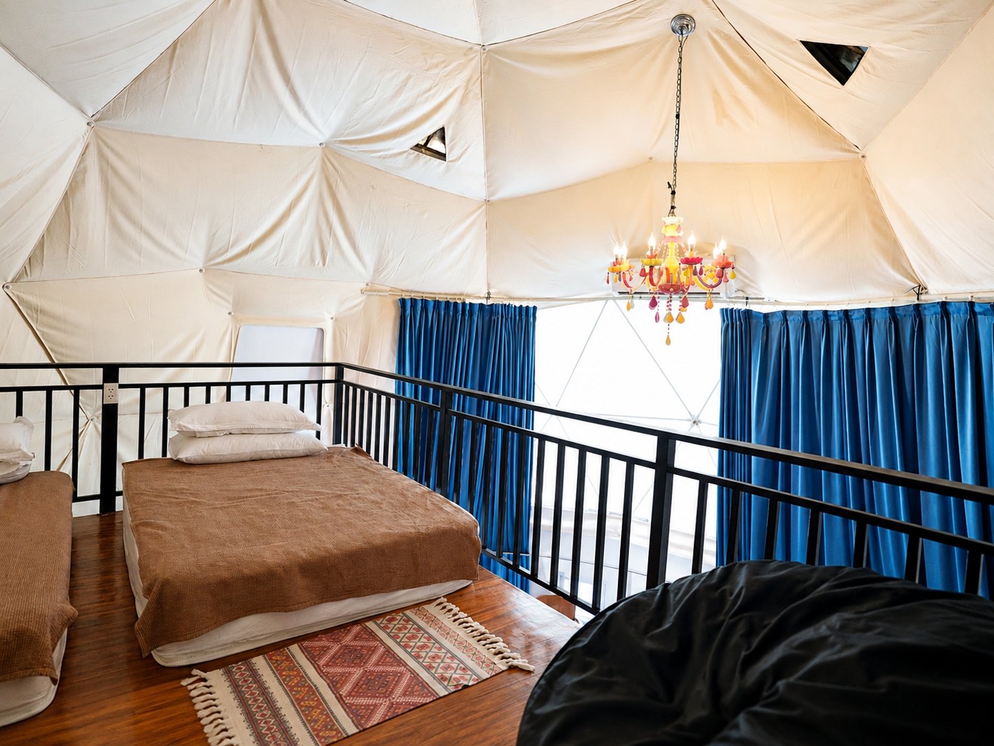 The dome mezzanine bedroom with chandelier, blue curtains and dome window