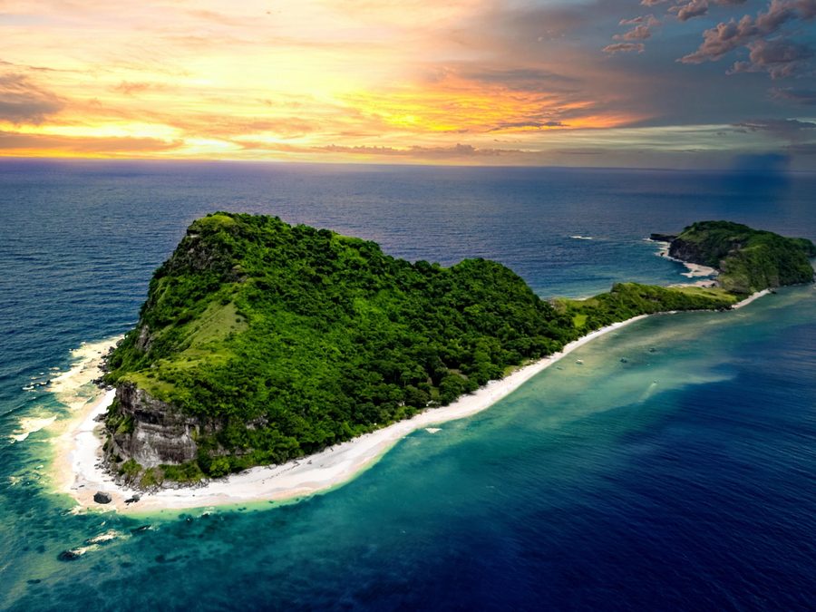 Aerial view of a lush island fringed with white sand near AmanDagat